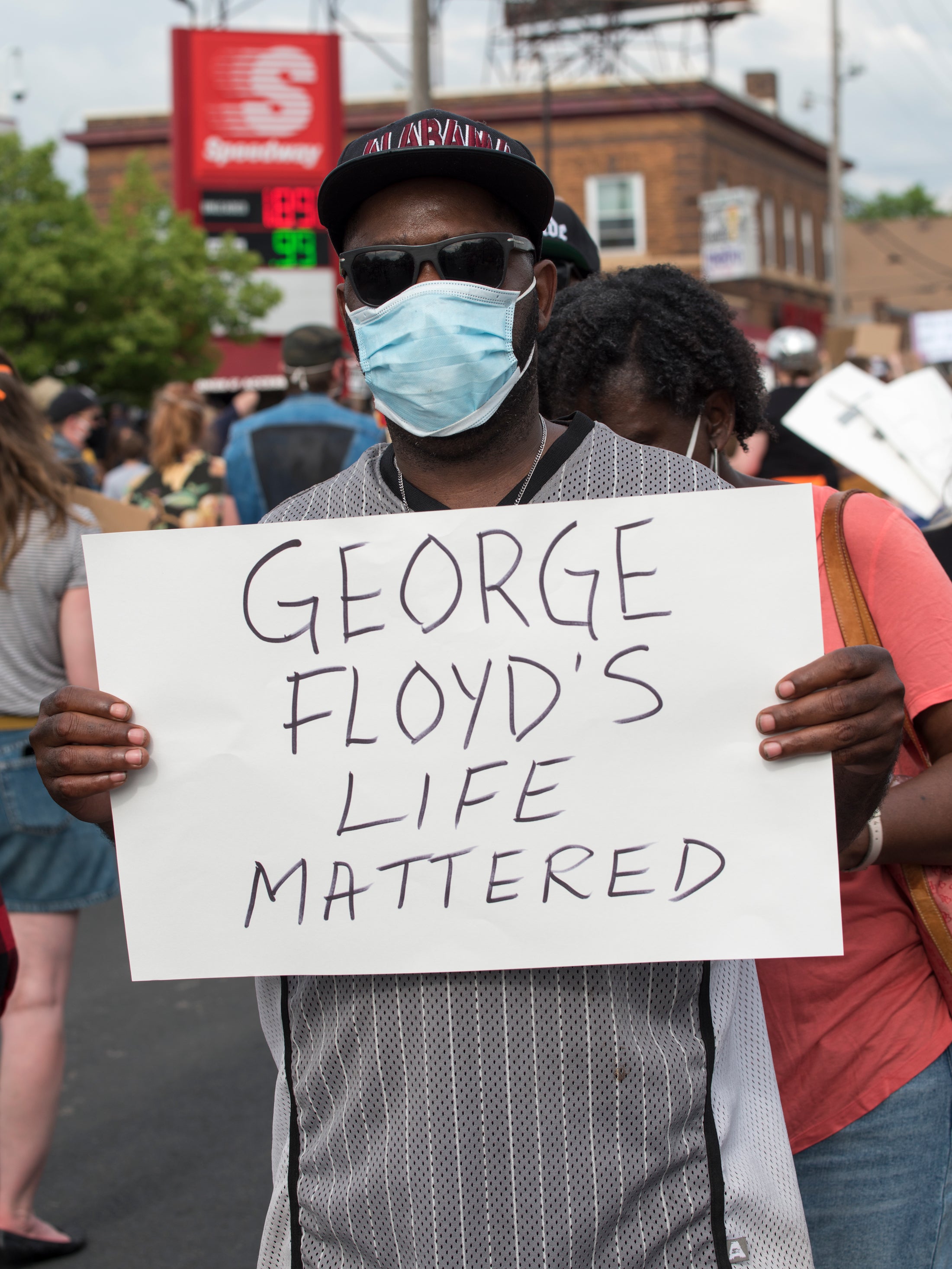 Man protesting police violence holding sign that reads "George Floyd's Life Mattered"