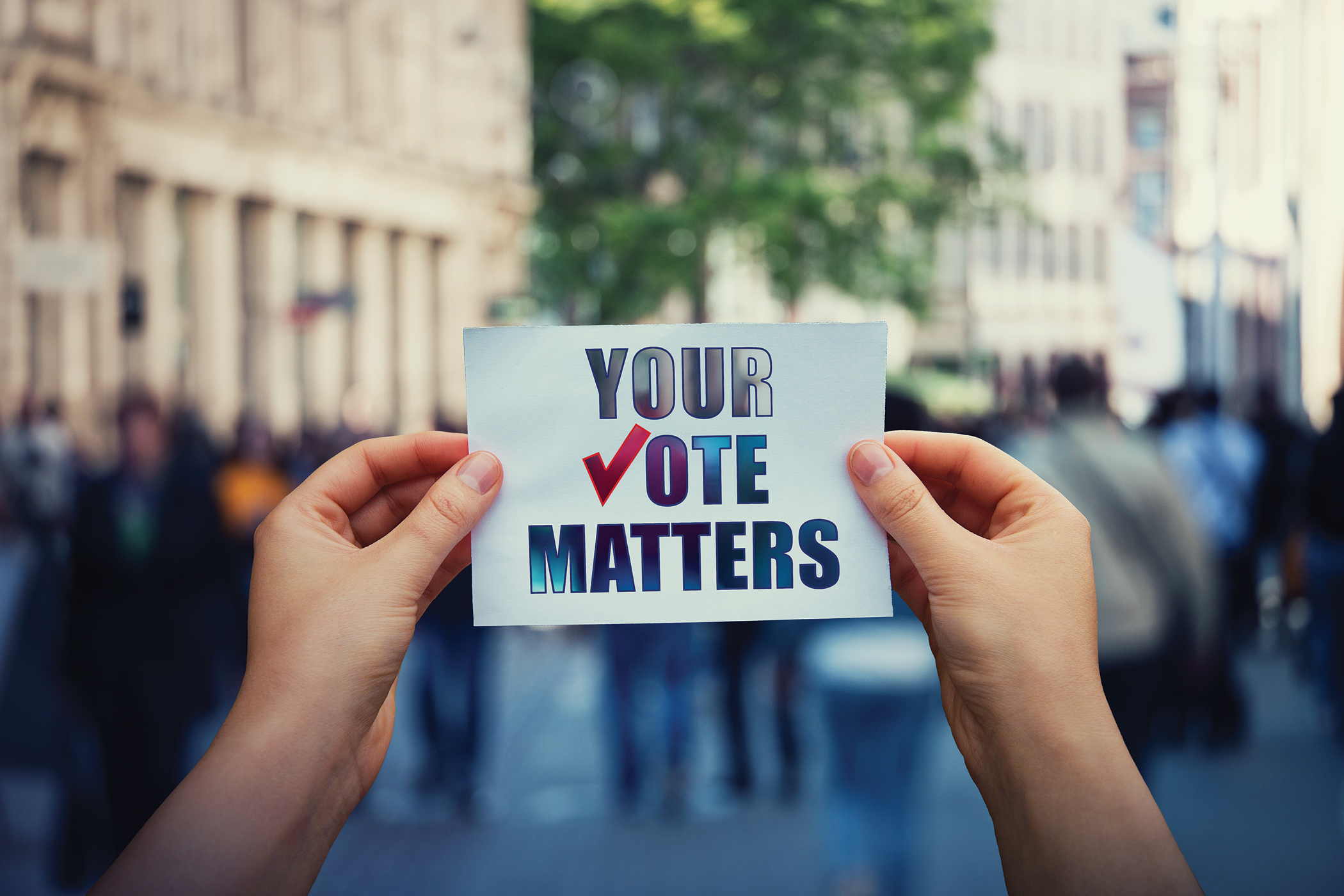 Hands hold a piece of paper with the message "Your Vote Matters"